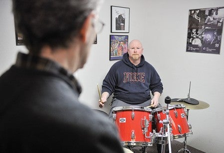 Rob Osmonson works on a kit behind Apold Music as Bill Apold watches during a lesson Tuesday morning. Eric Johnson/photodesk@austindailyherald.com