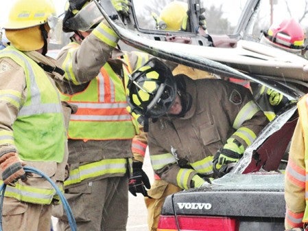 Firefighters perform a drill with a damaged car during a training exercise.