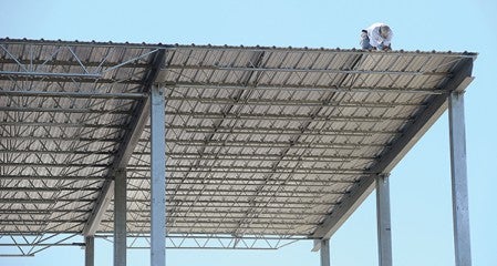 A construction worker works on the awning of the new grandstands Tuesday at the Mower County Fairgrounds.