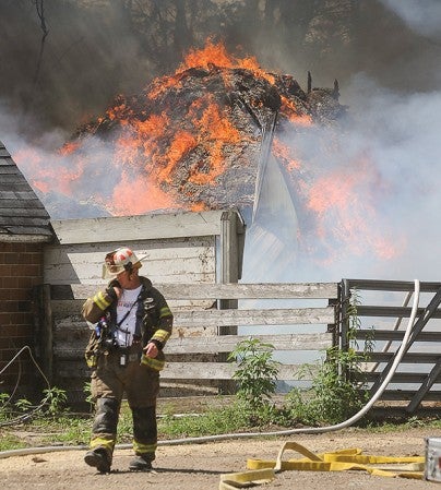 Austin Fired Department Commander Tom Schulte communicates with firefighters as a shed burns on Joe Sheedy's property northwest of Austin Tuesday afternoon.
