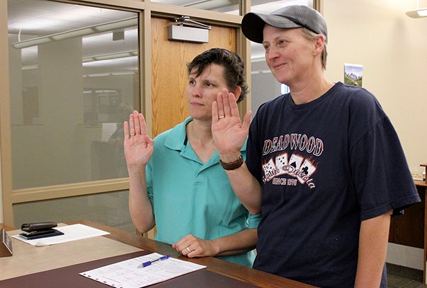 Virginia Chadbourne, left, and Della Hill raise their hands while applying for a marriage license Thursday at the Freeborn County Recorder’s office. Sarah Stultz/Austin Daily Herald