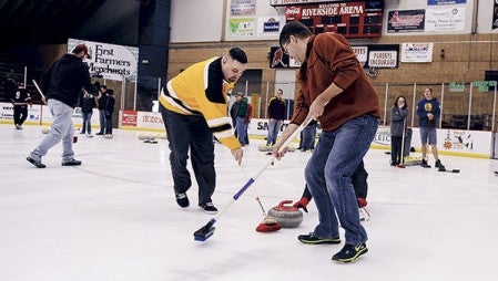 Aaron Keenan, right and Clint Narramore sweep in front of a curling stone during a curling open house Saturday afternoon at Riverside Arena. Eric Johnson/photodesk@austindailyherald.com