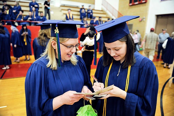 Ashley Betlach, left, and Courtney Zabel, both of Owatonna, sign a card for a teacher before Riverland Community College's commencement exercises Friday night at Austin High School. Eric Johnson/photodesk@austindailyherald.com