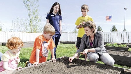 Hy-Vee nutritionalist Jen Haugen demonstrates how to plant spinach seeds during the planting of the One-Step Garden Wednesday afternoon. Photos by Eric Johnson/photodesk@austindailyherald.com