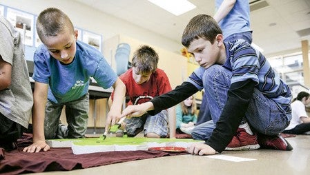 Robert Demick-Booth, from left, Elijah Hemann and Daniel Smith paint their puzzle piece.  