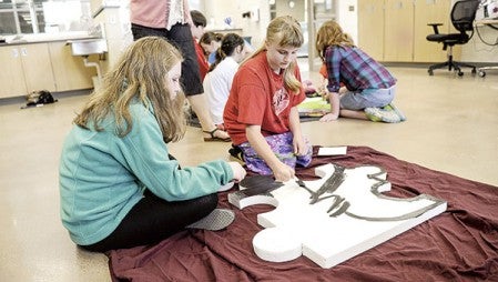 Lillian Dolph, right, and Olivia Johnson get to work on their puzzle piece Friday morning as the Peer Power Partners get to work on a project that will be displayed at the Austin ArtWorks Festival. 