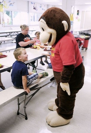 Three-year-old Bradley O’Connor smiles as Curious George comes up to say “hi” during a stop at Neveln Elementary School Thursday