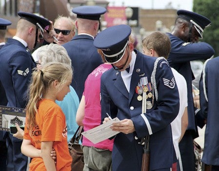 Staff Sgt. Daniel Sellstrom signs a program for 11-year-old Joslyn Cotton of Charles City, Iowa, after the United States Air Force Honor Guard Drill Team performed.