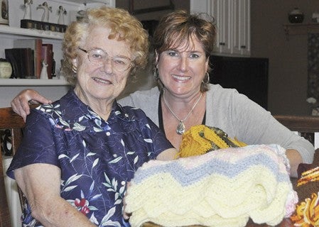 Dolores Jech and her daughter, Patti Nordin, sit by scarves and an afghan Jech has crocheted. 