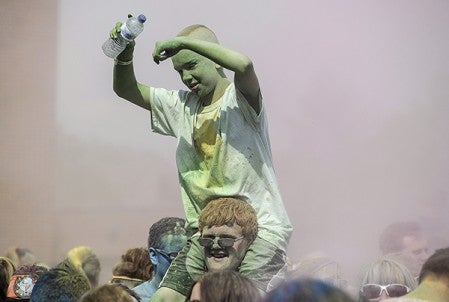 An unidentified boy, covered in colored powder, is carried through the crowd following last year’s Color Dash’s color explosion last year. Herald file photo