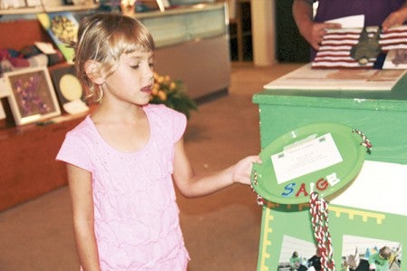 Amy Smith, 7, of the Cloverbud 4-H club shows off a sled she made for American Girl dolls as she set up in the 4-H building