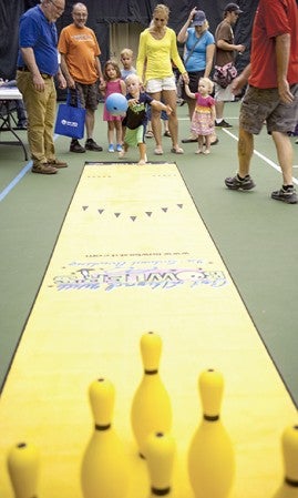 Four-year-old David Demro, with his mother, Marty Demro, and sister, two-year-old June Demro, takes a crack at bowling.