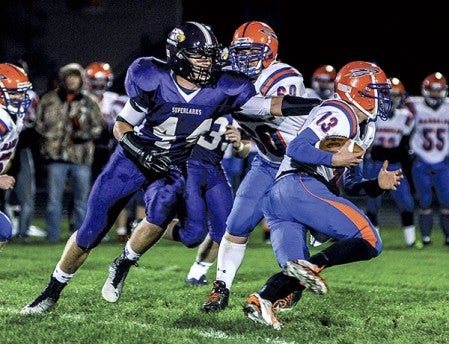 Grand Meadow's Connor Hartson reaches out for Randolph quarterback Luke Dubbels during the first quarter Friday night in Grand Meadow. Eric Johnson/photodesk@austindailyherald.com