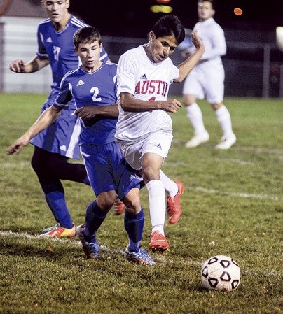 Austin's Roel Torres leaps past Kasson-Mantorville's Sam Wing during the first  half of their playoff game Saturday night at Art Hass Stadium. Eric Johnson/photodesk@austindailyherald.com