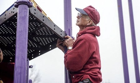 Roger Miner checks a level as he helps construct playground equipment in the Brownsdale Park Friday afternoon. Eric Johnson/photodesk@austindailyherald.com