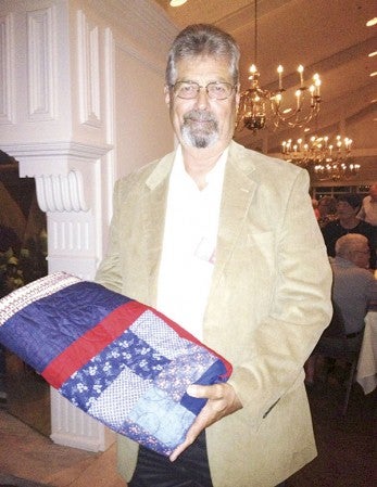 Veteran Marc Cleveland of Austin stands with the quilt he received through the Quilts of Valor program. Veterans in the Austin High School class of 1964 received quilts as a thank-you for their service at the 40th class reunion in September. Photo provided by Bonni Cook