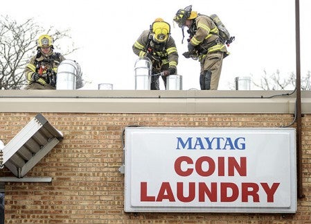 Austin firefighters check the vents on the roof of the Maytag Coin Laundry Wednesday afternoon after a dryer fire was knocked down. Eric Johnson/photodesk@austindailyherald.com