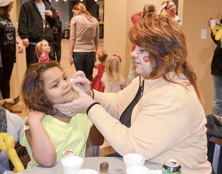 Makkel Gibson, 7, waits as Theresa Miller applies a temporary tattoo at Cornerstone Church. 