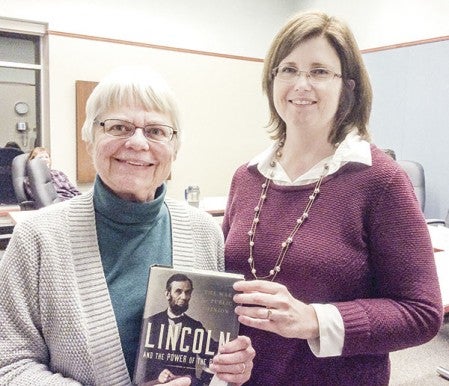 Becky Repinsky is thanked with a new library book purchased in her honor by current board chair Julie Schramek Monday evening. Repinski completed nine years on the library’s board of trustees, the maximum possible. She served on several library committees and was chair of the board for several years. Photo Provided