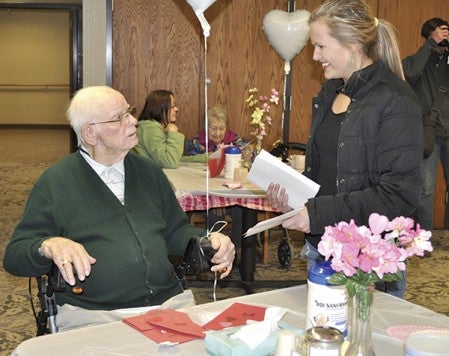 Austin High School senior Jenna Williamson, right, gives a card to seniors at St. Marks Living Friday. The National Honors Society was one of several groups to give Valentine's Day cards to area seniors. Trey Mewes/trey.mewes@austindailyherald.com