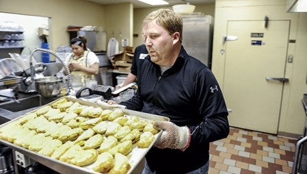 Chef Wade Kolander carries a pan full of beef and bean empanadas, fresh out of the oven.