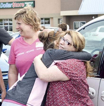 Tina Janning hugs a volunteer from the Car Care Clinic in front of her white 1998 Chrysler Town Country van, which was given to her at the clinic to replace her old vehicle.  Jenae Hackensmith/jenae.hackensmith @austindaily herald.com