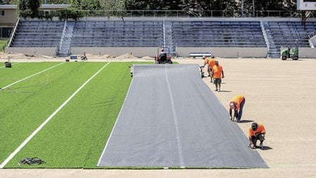 Crews were busy laying down the artificial turf over Art Hass Stadium Friday afternoon. The turf will not only cover Art Hass but the practice field inside Larry Gabrielson Track and Field to the north. Eric Johnson/photodesk@austindailyherald.com