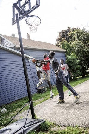 Dongoin Deng heads into the basket as he shoots around with his twin brother Ngor and older brother Deng. Eric Johnson/Eric Johnson/photodesk@austindailyherald.com