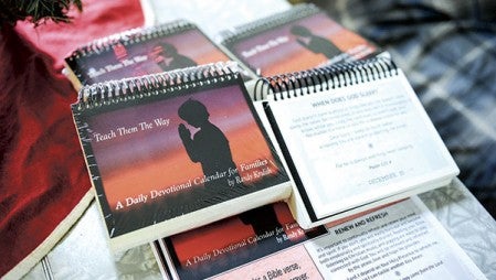 Copies of Randy Krulish’s “Teach Them The Way” sit on a table in his Lyle apartment.