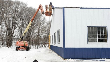 Construction workers work on the roof of the old Oasis Ballroom, which is being converted to Precision Signs’ production facility. 