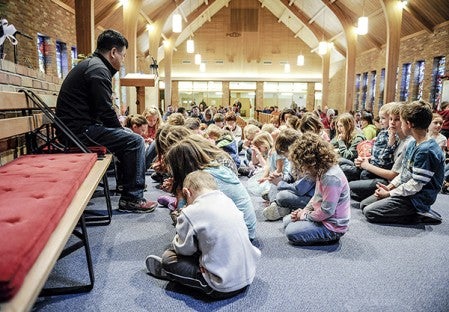 Westminster Presbyterian Church associate pastor Mark Lee prays with children during the Westminster Easter Celebration Saturday morning. Eric Johnson/photodesk@austindailyherald.com