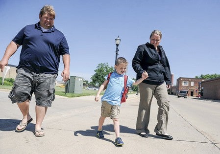 Four-year-old Logan Johnson walks across the street with dad Brandon Johnson and mom Jessica Johnson Friday morning. Logan is working to overcome childhood apraxia of speech. Eric Johnson/photodesk@austindailyherald.com