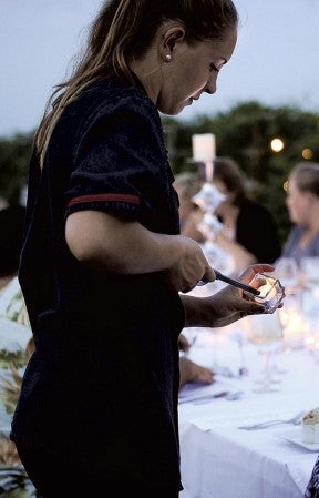 The lighter lights the face of Jessi Kaster as she relights a candle during the Dining in the Vines event at Four Daughters Winery and Vineyard. Jora Bothun/jora.bothun@austindailyherald.com