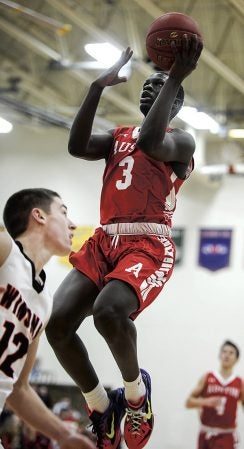 Austin’s Moses Issa gets a lay-up over Winona’s Easton Gamoke during the first half Thursday night in Packer Gym. Eric Johnson/photodesk@austindailyherald.com