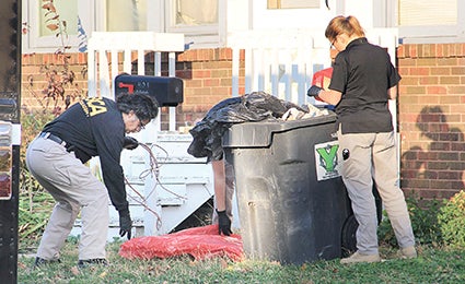 Investigators with the Minnesota Bureau of Criminal Apprehension take evidence from a trash bin outside a home on the 400 block of South Main Street in Austin Thursday afternoon. Herald file photo