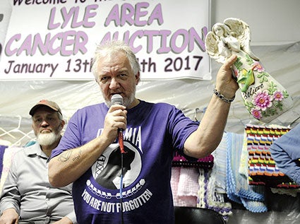 Curt Gilbert holds up an angel statue that his late partner Theresa Gamble purchased at the Lyle Area Cancer Auction. Gilbert turned around and donated it back to the auction this year. 