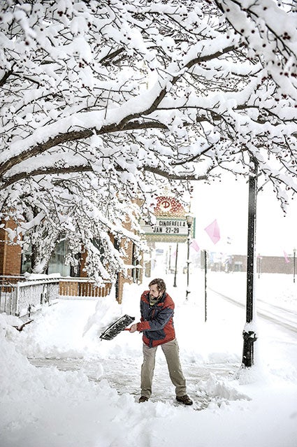 Jason Richard, owner of Austin Acupuncture, shovels snow from the walkway of his business underneath a canopy of snow. 