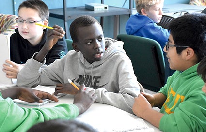 Sixth graders, from left, Winston Walkup, Buoy Koak, Anthoni Garcia and Adan Lagunas talk about who they believed was the most evil person during an hour of writing with author Jason Glaser at Pacelli Catholic Schools on Monday.