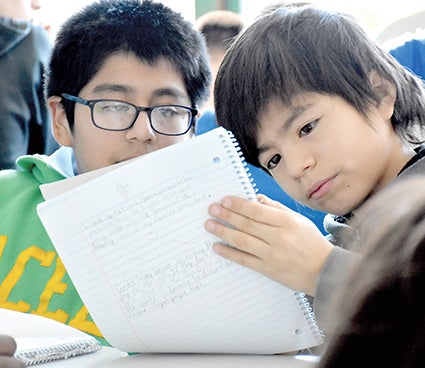 Sixth graers Anthoni Garcia and Adan Lagunas check out a piece of writing during author Jason Glaser's visit to Pacelli Catholic Schools.