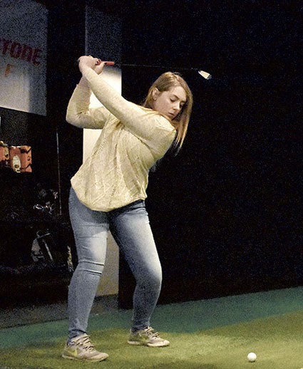 Blooming Prairie senior Taylor Christianson tees off at the trackman indoor golf simulator. 