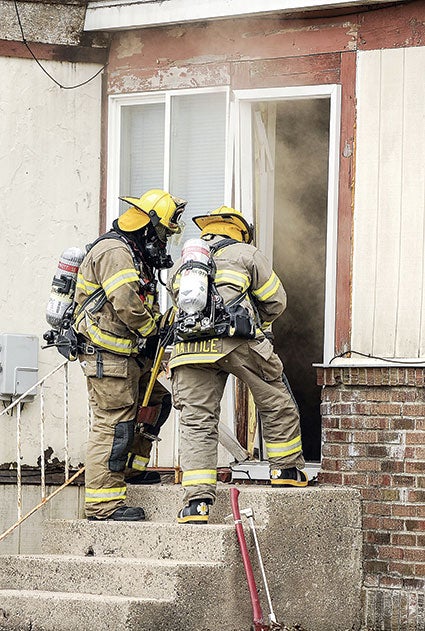 Firefighters breach a door to ventilate.