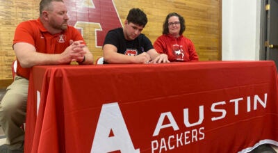 Austin senior Sam Winkels signs his national letter of intent to wrestle at St. Cloud State University as his parents Mark and Dayna look at AHS Tuesday. Rocky Hulne/sports@austindailyherald.com