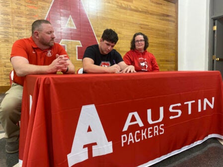 Austin senior Sam Winkels signs his national letter of intent to wrestle at St. Cloud State University as his parents Mark and Dayna look at AHS Tuesday. Rocky Hulne/sports@austindailyherald.com