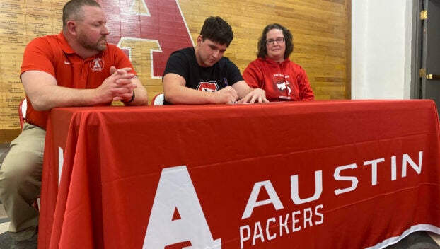 Austin senior Sam Winkels signs his national letter of intent to wrestle at St. Cloud State University as his parents Mark and Dayna look at AHS Tuesday. Rocky Hulne/sports@austindailyherald.com